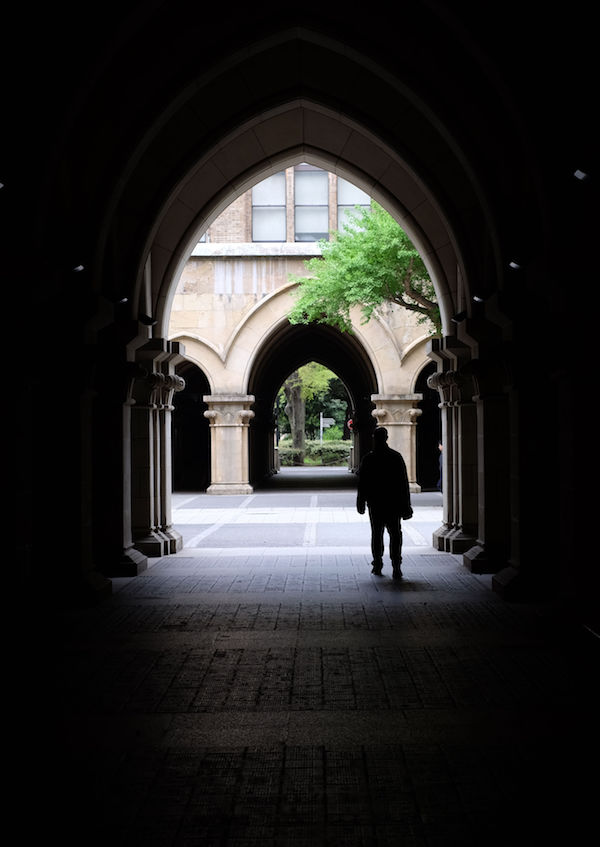 Una persona andando entre arcos y sombras en la Universidad de Tokio